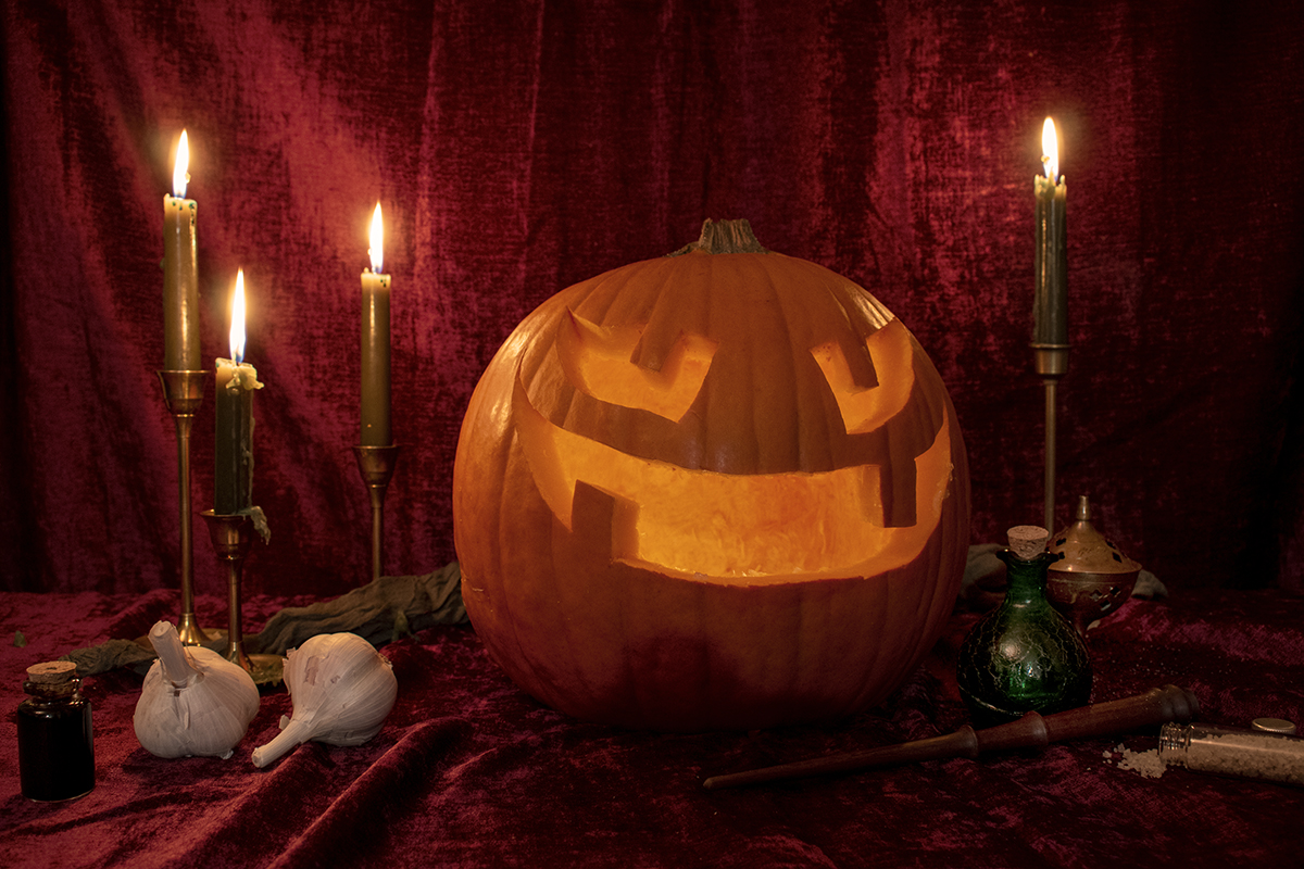 一张铺着天鹅绒桌布的桌子上点亮了一盏大南瓜灯，桌子周围摆满了蜡烛、魔药、大蒜和一根魔杖。