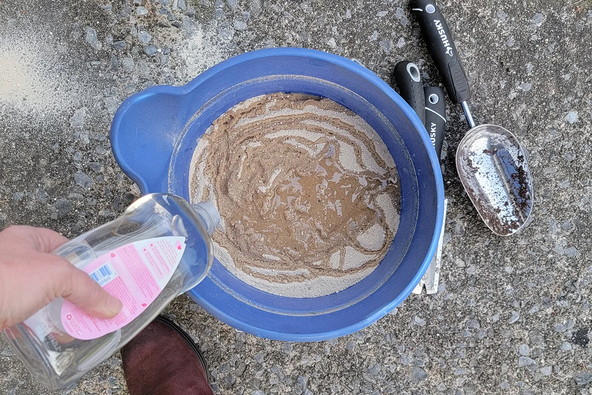 Bucket of sand with mineral oil being poured over it.