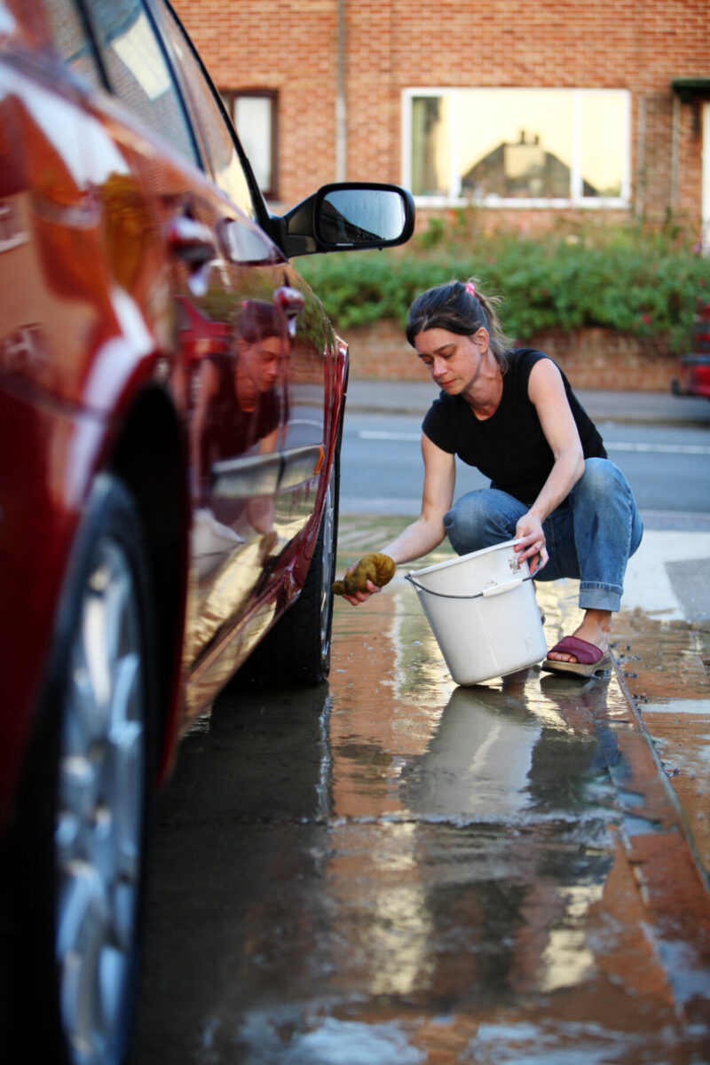 女人用水桶和勺子洗车。