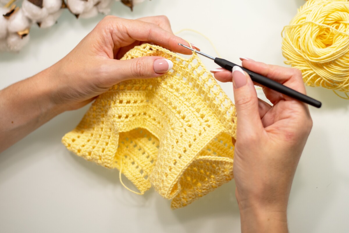 女人的手用黄色的纱线编织